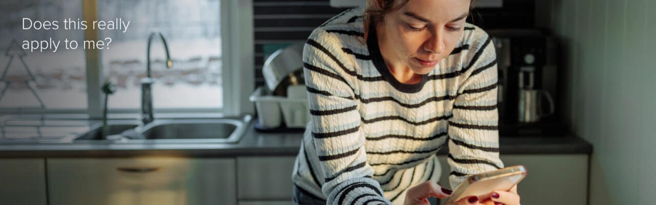 Woman looking at her phone in a kitchen, appearing concerned while reviewing health information