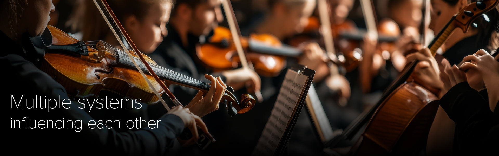 Orchestra musicians playing string instruments together, with multiple performers actively engaged at the same time